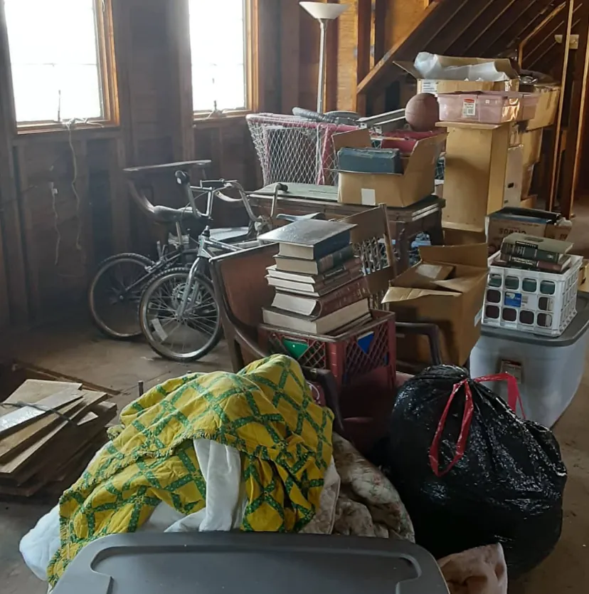 Boxes, books, a bicycle, and belongings in an attic