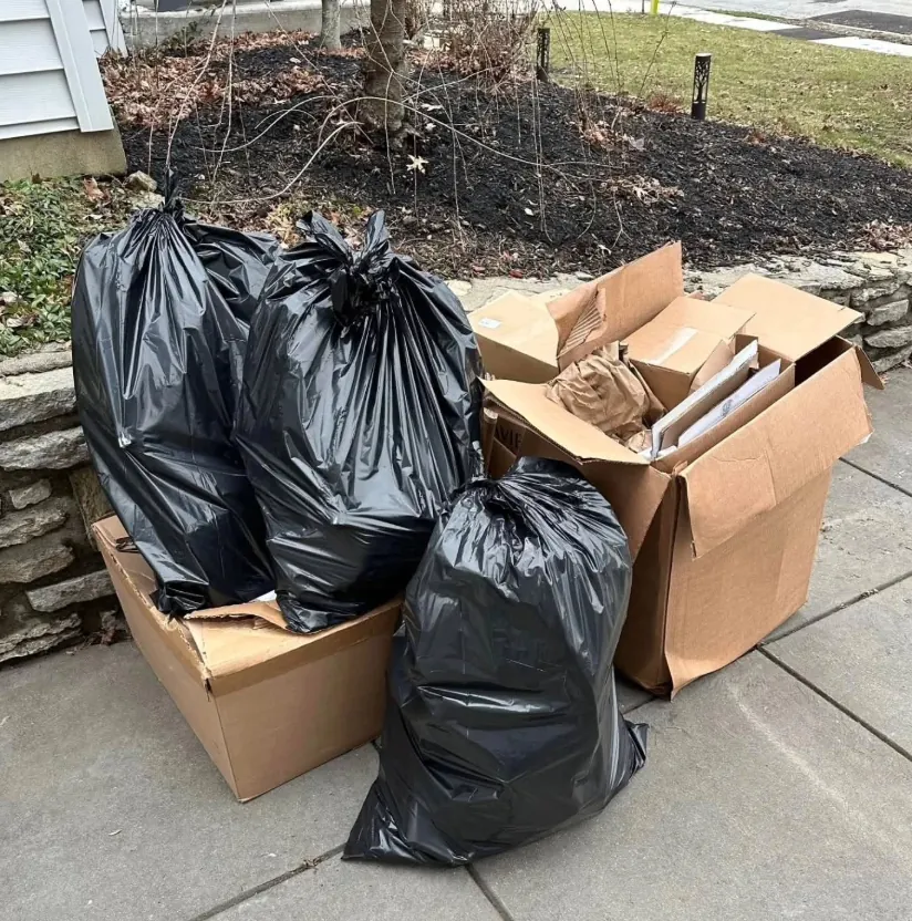 Tied trash bags and cardboard boxes on a walkway
